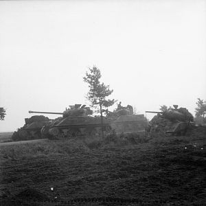 Irish Guards Group, Sherman Firefly tank advances past Sherman tanks knocked out earlier during Operation 'Market-Garden', 17 September 1944; IWM BU 926